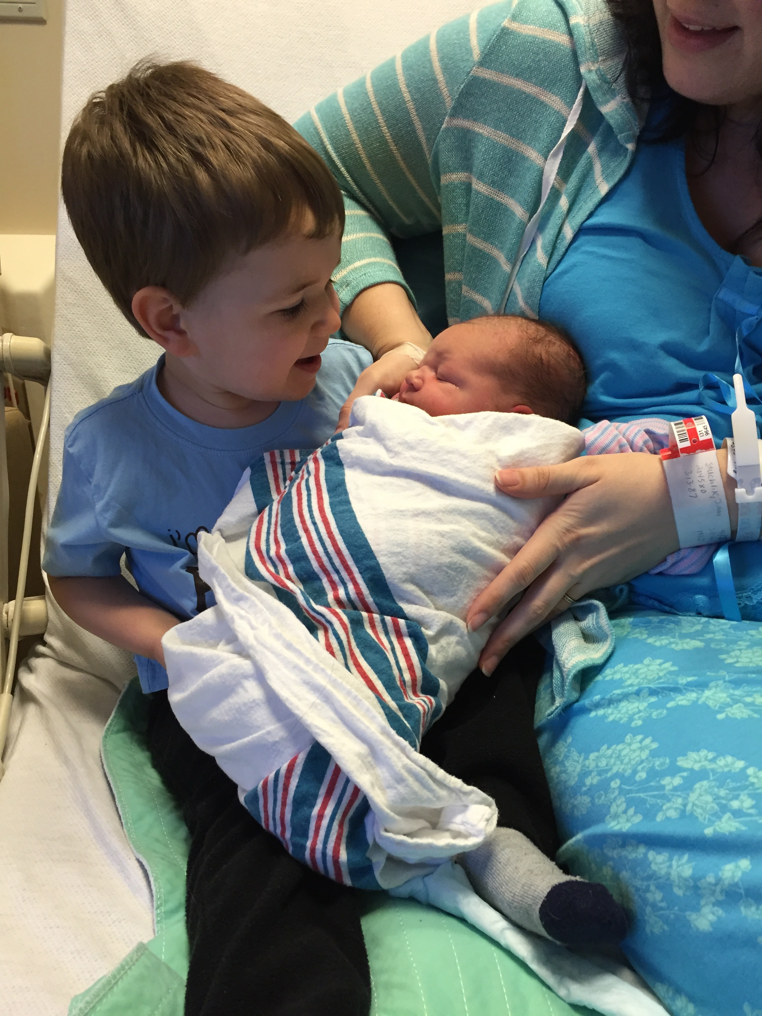 little-boy-welcoming-his-newborn-brother-with-mother-into-family