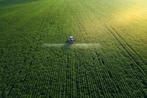 aerial shot tractor spreading herbicides over field