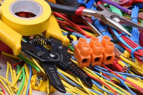 A close-up of an electrician's tools including wires, electrical tape, and pliers