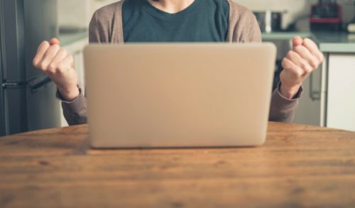 person-sitting-at-laptop-with-fists-clenched-triumphantly