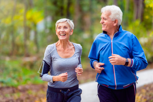 smiling senior couple jogging in the park