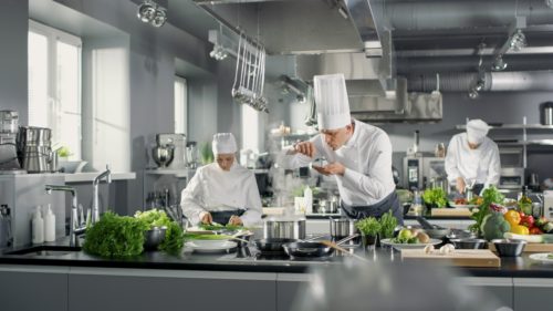 chef-plating-food-in-busy-restaurant-kitchen