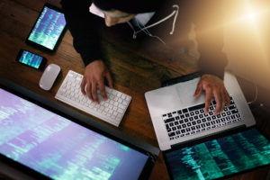 man writing code with two computer monitors