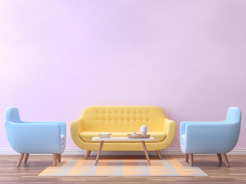 A pastel yellow couch and two light blue armchairs on a throw rug