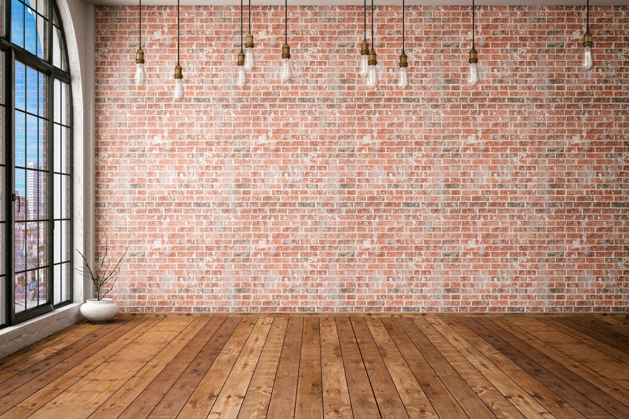 a-room-with-wood-flooring-brick-wall-and-several-bare-lightbulbs