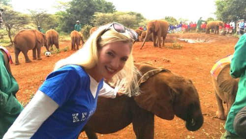 woman posing with baby elephant