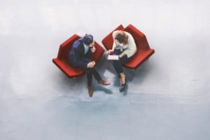 man-and-woman-sitting-in-office-chairs-discussing-professional-workspace