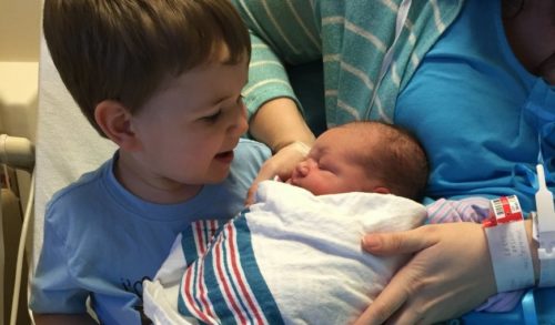 little-boy-welcoming-his-newborn-brother-with-mother-into-family